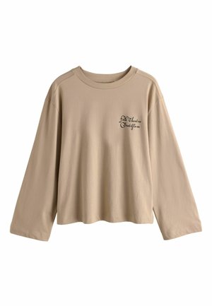 Tricou din bumbac bej, cu mânecă lungă și croială lejeră. Are un decolteu rotund și broderie pe față cu "Teatrul Popular Bratislava."