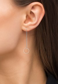 Strieborné náušnice s tenkým, štíhlym reťazcom a kruhovým akcentom na konci, ktoré zdôrazňujú minimalistický dizajn a elegantný povrch.