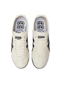 Pair of off-white Onitsuka Tiger sneakers with black stripes, laces tied, and patterned insoles, viewed from above on white background.
