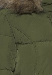 Olivengrøn pufjakke med en fluffy brun pelskrave, der har et quiltet design og en glat, blank tekstur over stoffet.