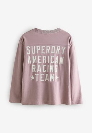 Långärmad T-shirt med rund hals i ljusrosa tyg. Har vit texturerad tryck: "SUPERDRY AMERICAN RACING TEAM" med två stjärnor.