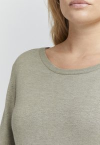 Olivenfarget genser med ribbestrikket rund hals, laget av mykt stoff, med en jevn tekstur og en tettsittende silhuett.