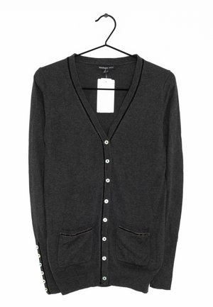 Donkergrijze cardigan van zacht materiaal, met een V-hals, twee voorzakken en knoopsluiting. Afgemeten met contrasterende bies.