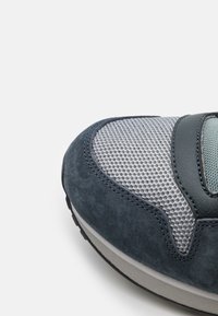 Sko med en överdel i mörkblå mocka och grått mesh, med en slät gummisula och en strukturerad design. Accentuerad med en syntetisk överdrag.