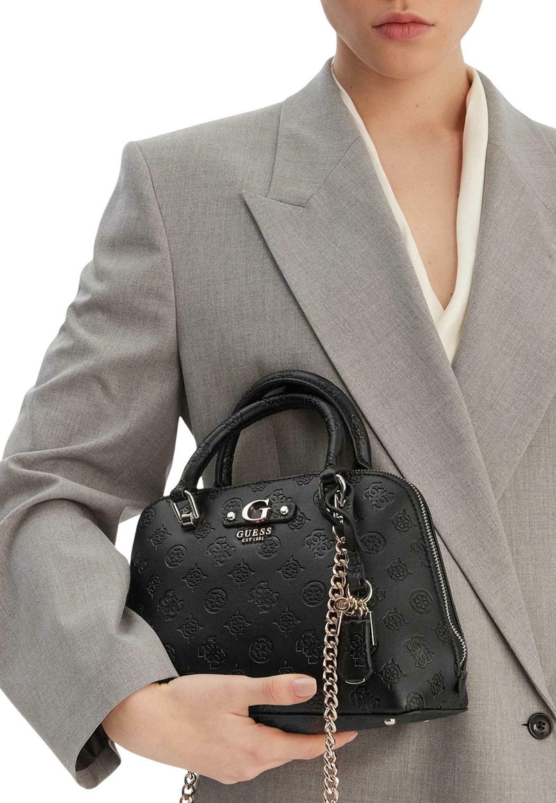 Sac à main en cuir noir avec logo embossé, accessoires en argent et bandoulière en chaîne. Forme compacte avec deux poignées et finition texturée.