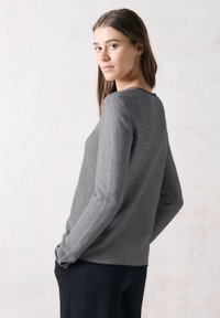 Långärmad topp i grå och svarta ränder, med en rund halsringning och avslappnad passform. Lätt och mjukt tyg med sidofickor.
