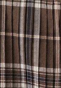 Tissu à motif à carreaux marron, beige, noir et blanc avec des lignes verticales et horizontales, texture visible et plis.