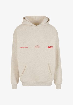 Beige hoodie gjord av bomullsblandning. Har en känguruficka, ribbade ärmslut och tryckta logotyper i rött på bröstet. Mjuk textur.