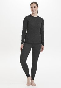 Grå långärmad topp och leggings set, tillverkad av ett texturerat material med kontrasterande sömmar och ribbade muddar, vilket ger en figurnära och flexibel design.