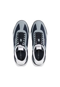 Zapatillas en tonos marino y gris, con una mezcla de materiales de ante y malla, cordones negros y un acento en el talón blanco. Logo de la marca visible en la lengüeta.