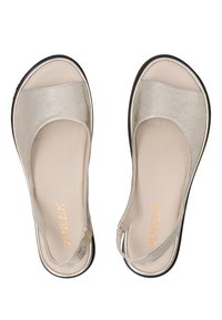 Metallisch goldene Sandalen mit einem geschwungenen Design, offenem Zehenbereich und verstellbarem Knöchelriemen. Glatte Oberfläche mit einem hellbeigen Fußbett und schwarzer Sohle.