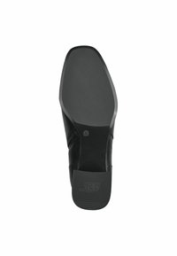 Sole della scarpa nera slip-on con superficie di presa texturizzata, bordo curvato e logo in rilievo. Presenta una finitura liscia e opaca e un'etichetta di misura.
