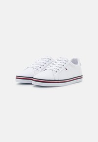 Sneakers bianchi in tela con design a basso profilo, dotati di suola in gomma piatta e strisce accentuate rosse e blu lungo il fondo. Con lacci frontali.