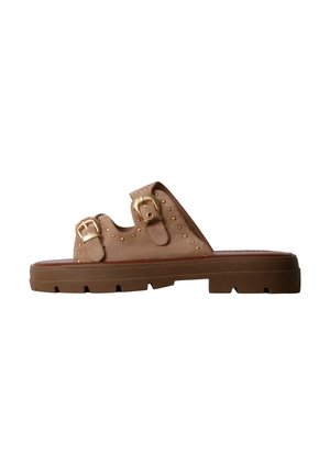 Sandale mule en daim marron avec double boucle dorée, détails cloutés et semelle épaisse en caoutchouc rainurée.