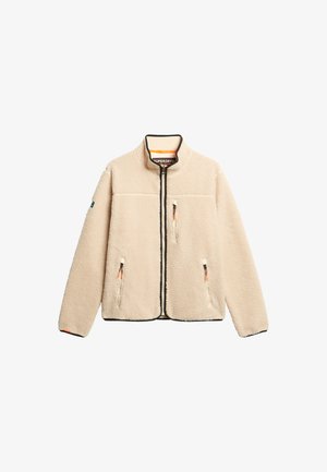 Giacca in pile beige con colletto alto, chiusura frontale con zip e due tasche laterali. Presenta bordi neri e tirazip a contrasto.