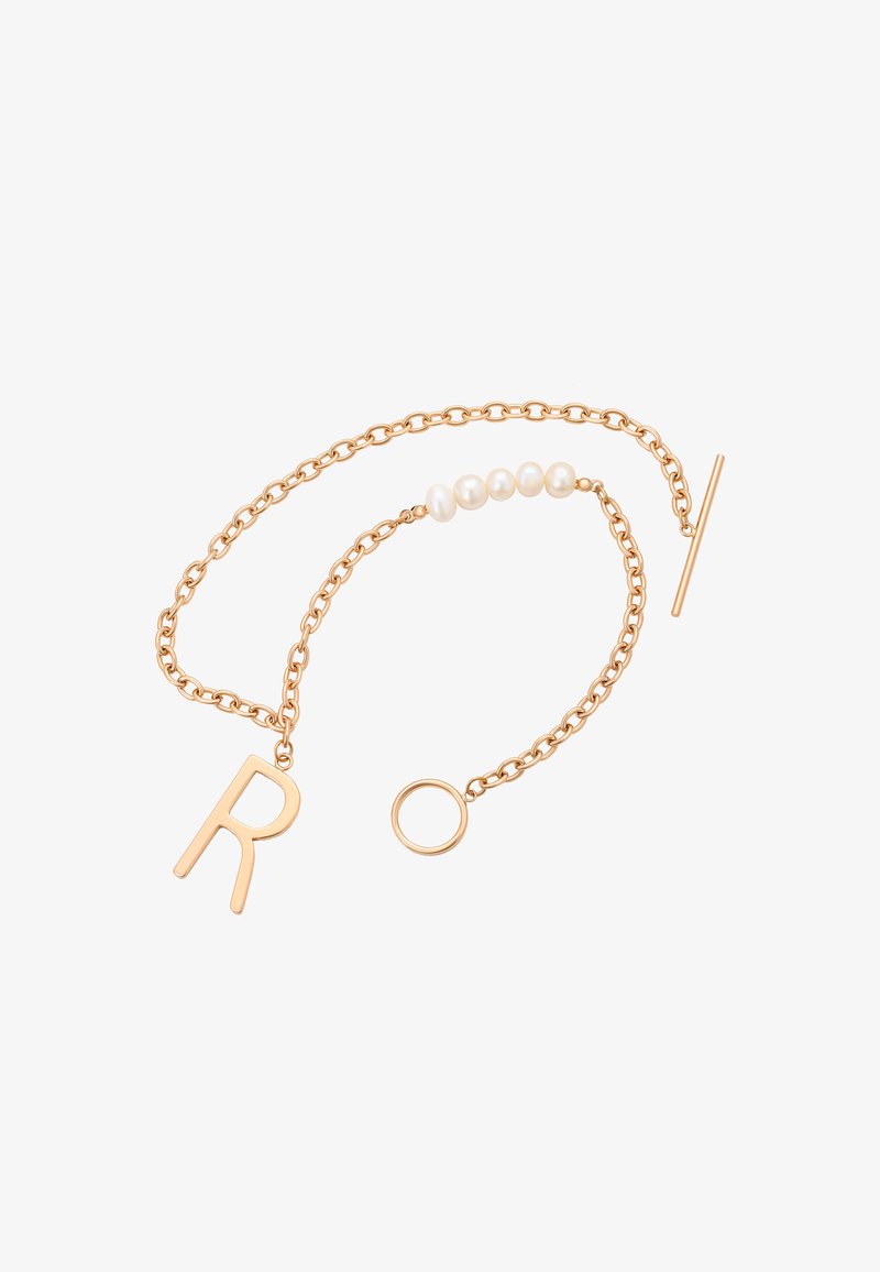Kuldtooni ahelaehe, millel on täht "R", viis valget pärlieksemplari, ringikujuline rõngas ja lülitusklambri disain. Sile metalline viimistlus.