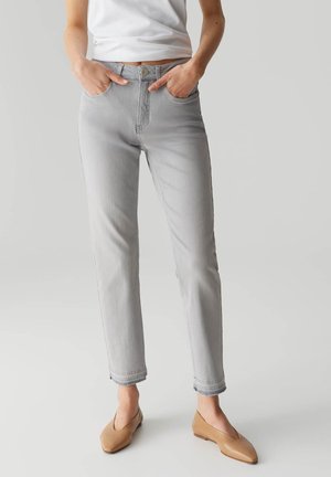 Lichtgrijze denim jeans met een slim fit, een klassiek vijf-pocketontwerp, hoge taille en opgerolde uiteinden, gecombineerd met lichtbruine flats.