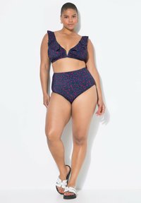 Bikini s vysokým pasem v navy a růžovém leopardím vzoru. Volánkový top s výstřihem do V, odpovídající vysoký pas. Nosené s bílými nazouvacími sandály.