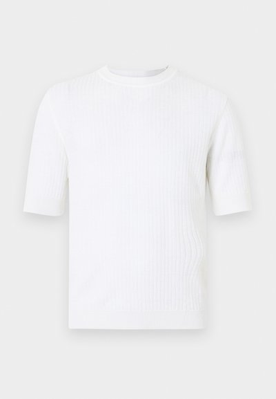 Pull en maille côtelée blanc à manches courtes, col rond et silhouette ajustée. Texture lisse avec détails côtelés sur l'ensemble.