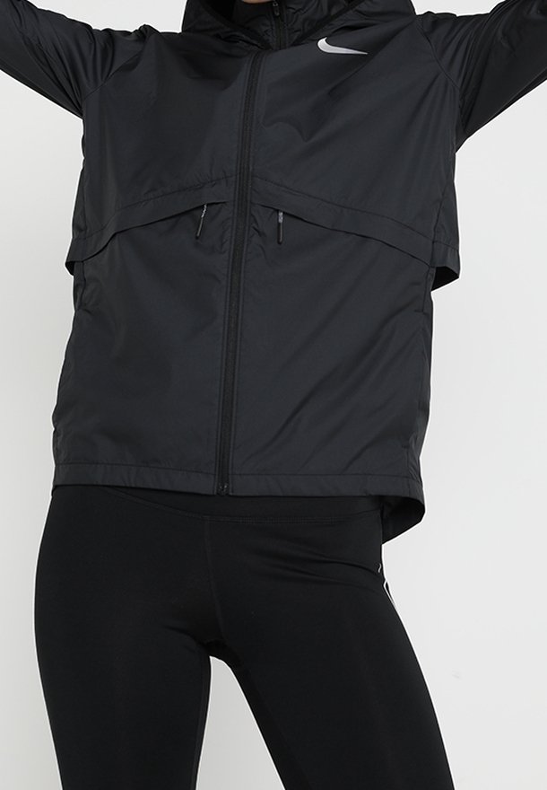 Veste coupe-vent Nike noire avec zip sur le devant, capuche et design en superposition. Présente un logo contrasté sur la poitrine et des poches zippées sur les côtés.