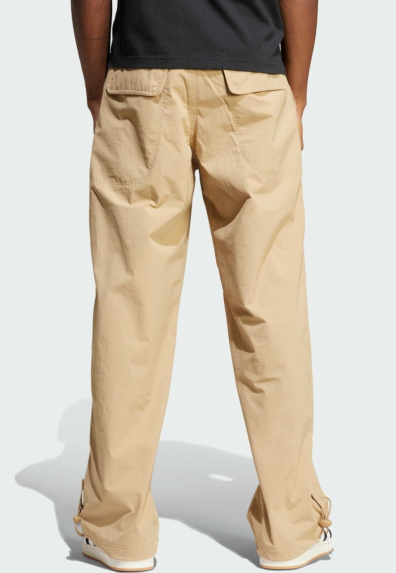 Pantaloni cargo beige con vestibilità rilassata, due tasche posteriori e polsini regolabili, realizzati in materiale leggero.