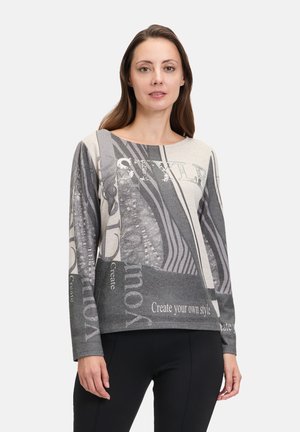 Gray and beige long-sleeve top featuring abstract patterns and text, with a boat neckline and relaxed fit. Smooth texture.