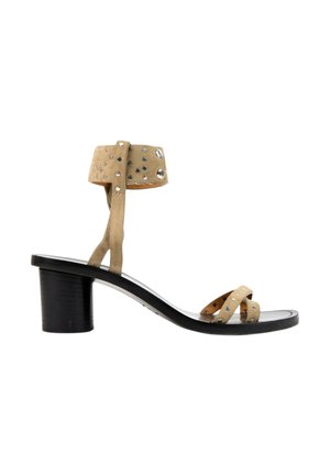 Beige ruskind sandal med små sølv nitter, lav sort blokhæl, åben tå og ankelrem med spænde.