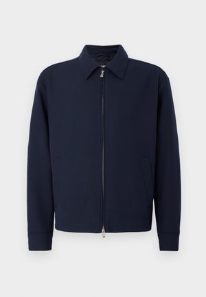 Marineblauwe ritsjack met kraag, lange mouwen, twee zijzakken en zilveren ritsluiting op een effen witte achtergrond.