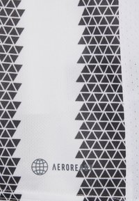 Tissu blanc présentant un motif de triangles noirs le long d'un bord, avec la marque "AEROREADY" et une icône de globe imprimée en dessous.