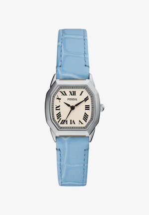 Fossil-klocka med ett oktagonalt silverhölje, krämfärgad urtavla, svarta romerska siffror och ett ljusblått, texturerat läderarmband.