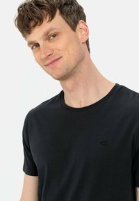 Sort bomulds T-shirt med rund halsudskæring, korte ærmer og et lille logo på brystet. Glat tekstur og klassisk pasform.