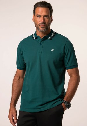 Polo de color verde oscuro con mangas cortas, cuello acanalado con rayas blancas y pequeño logo bordado en el pecho. Textura de tela suave.