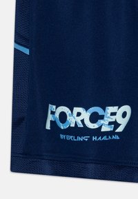 Námorné športové šortky s priehľadnými stranami, s nápisom "FORCE9" v opotrebovanej modrej farbe a nápisom "od Erlinga Hålanda" vytlačeným čierne.