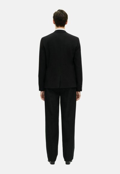 Schwarzer maßgeschneiderter Anzug mit einem strukturierten Blazer und locker sitzenden Hosen. Glattes Material mit einem klaren Rückendesign und ohne sichtbare Muster oder Akzente.