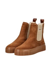 Braune Wildleder-Stiefeletten mit elastischen Seitenteilen, strukturierten beigefarbenen Akzenten und einer chunky braunen Gummisohle mit vertikalen Rillen.