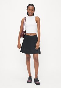Fehér bordázott crop top, hullámos széllel, fekete harangszoknya és fekete platform loaferek lila részletekkel. Bordó keresztpántos táska is tartozik hozzá.