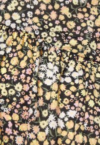 Tecido preto enfeitado com um padrão floral, apresentando flores amarelas, rosas e brancas. O material possui uma textura suave com detalhes plissados.