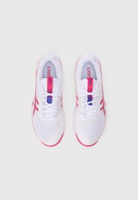 White athletic shoes with pink accents, featuring a mesh upper, lace closure, and textured soles. The logo is displayed on the tongue and side.