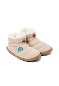 Zapatillas suaves beige con exterior de pana, forro interior de felpa y suela de goma. Presentan un cierre rojo y un detalle del logotipo azul.