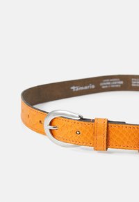 Ceinture en cuir orange avec un motif texturé en écailles, ornée d'une boucle en métal de couleur argent et de détails de couture.