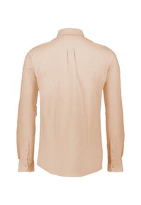 Camisa de lino de manga larga en melocotón claro con cuello abotonado, detalle de pliegue en la parte posterior y puños abotonados. Textura suave y corte relajado.