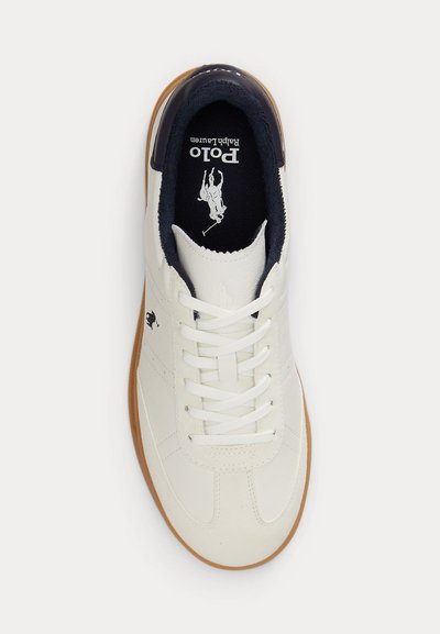 Λευκό δερμάτινο αθλητικό παπούτσι με μπλε εσωτερική επένδυση, λευκά κορδόνια, καφέ σόλα και το λογότυπο Polo Ralph Lauren ορατό στο εσωτερικό και στο πλάι.