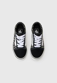 Baskets en toile noires avec des lacets blancs, présentant un motif à pois, des accents blancs et un design à bout rond. Semelle offrant une bonne adhérence.