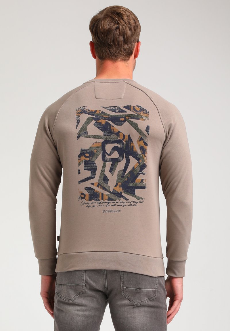 Beige sweatshirt with a textured back graphic in dark blue, green, and orange abstract patterns, featuring a curved hem and ribbed cuffs.