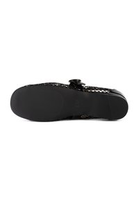 Chaussure plate noire avec dessus en mesh et bride à boucle, vue du côté de la semelle sur fond blanc.