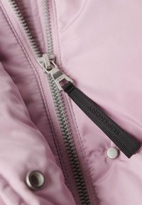 Rosa puffjacka med insidan som visar en grå dragkedja, silverfärgad hårdvara, en svart dragkedja med "Superdry"-text och en knappdetalj.