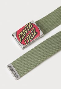 Green woven belt featuring a metallic silver buckle with a circular red logo that reads "SANTA CRUZ" in bold yellow lettering.
