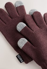 Fingervarmehandsker i bordeaux strik med grå teksturerede fingerspidser. Har en vævet etiket med "BAKER" på siden. Blødt materiale og tæt pasform.