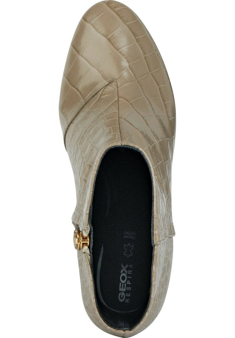 Beige Leder Schuh mit Krokodilprägung, spitzem Zeh und seitlichem Reißverschluss mit goldenen Beschlägen. Schwarzes Fußbett im Inneren sichtbar.