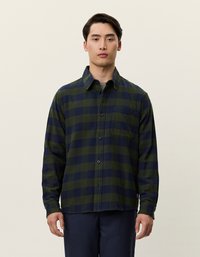 Koszula flanelowa w kraciasty wzór w ciemnozielonym i granatowym kolorze, z zapinaniem na guziki, długimi rękawami i kieszenią na piersi. Gładka faktura materiału.